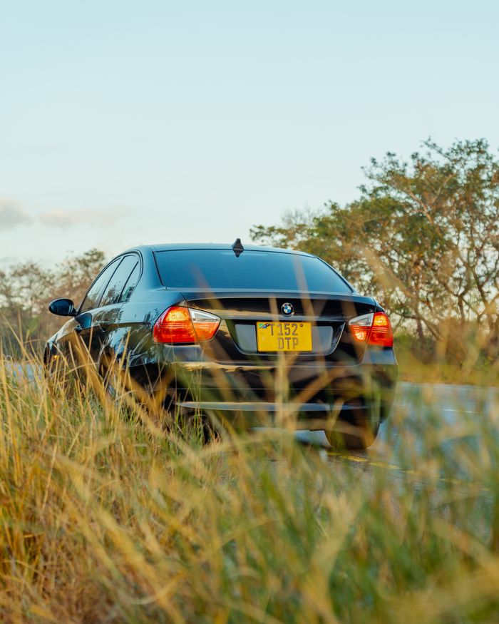 Black BMW sedan parked on grass beside a road, Morogoro, Tanzania.